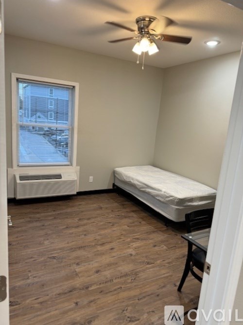 A bedroom with a bed, a table, and a window.