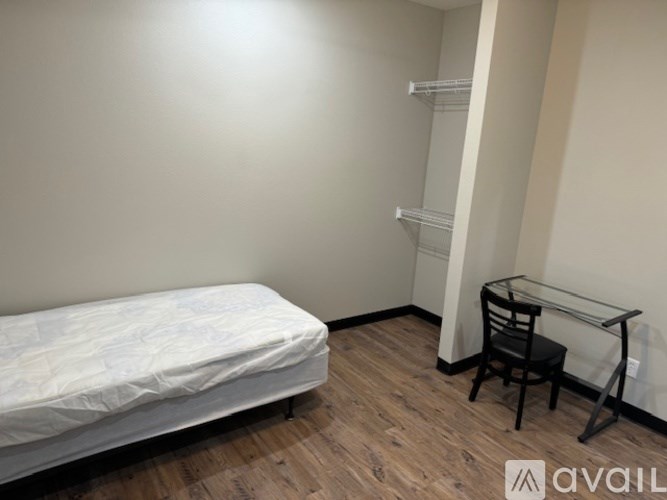 A bedroom with a bed, chair, and desk.