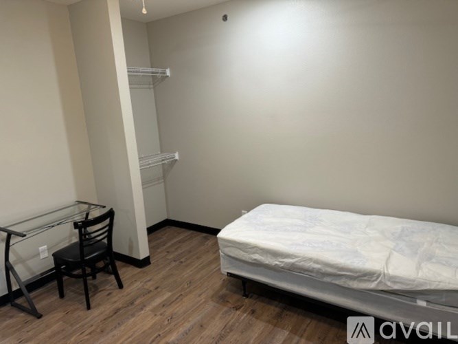 A bedroom with a bed, chair, and shelves.