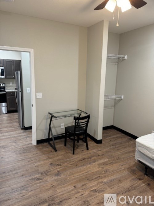 A room with a glass table and chairs and a bed in the corner.