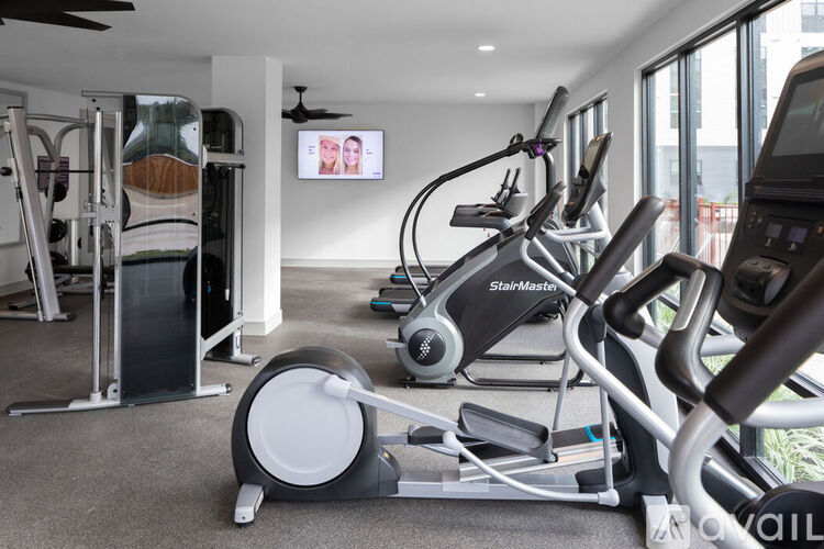 A gym with a row of treadmilers and a television mounted on the wall.