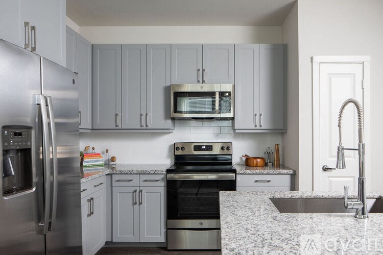 A kitchen with a stainless steel refrigerator and a black stove top oven.