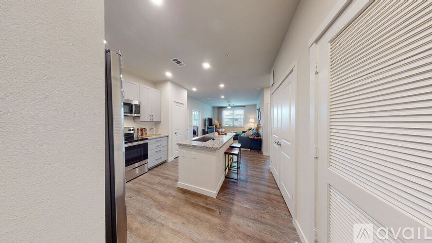 A modern kitchen with white cabinets and a wooden floor.