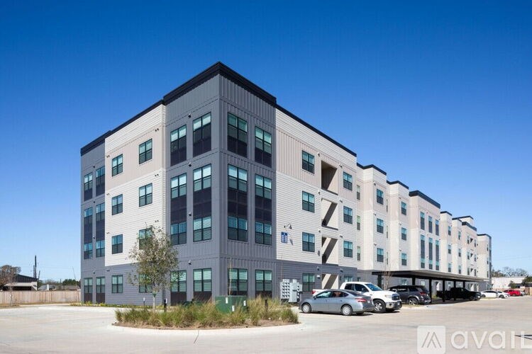 A modern multi-story building with a parking lot in front.