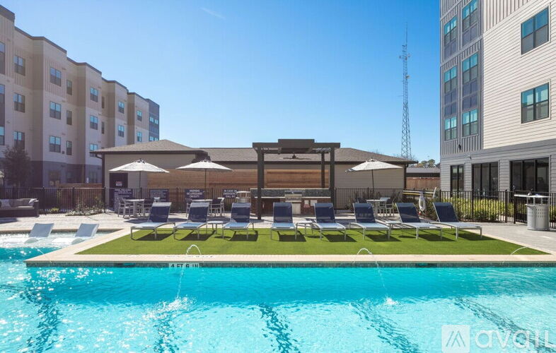 A pool with chairs and umbrellas in front of a building.