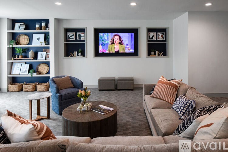 A living room with a couch, a coffee table, and a television displaying a woman.