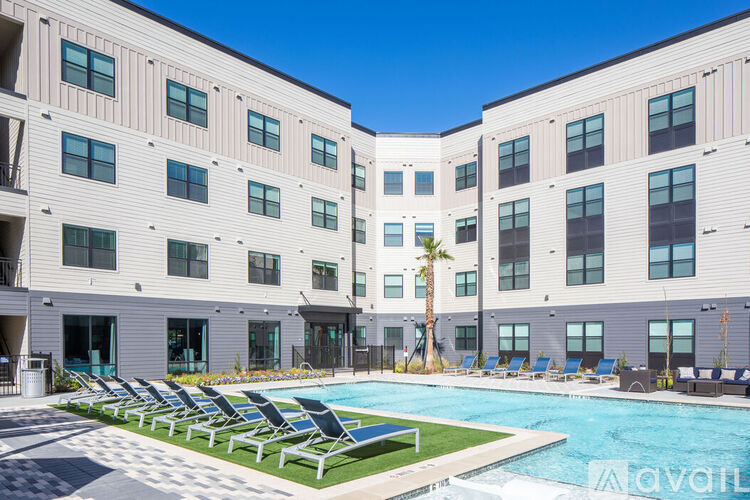 A swimming pool is surrounded by lounge chairs in front of a building.