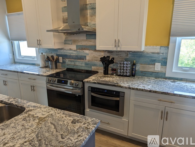 A kitchen with a granite countertop and a stone backsplash.