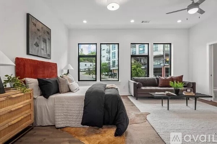 A bedroom with a bed, a couch, and a ceiling fan.