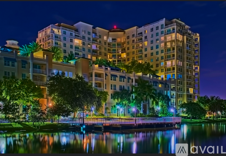 A large building with a pool in front of it is lit up at night.