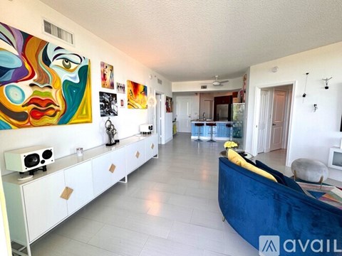 A living room with a blue couch and a painting on the wall.
