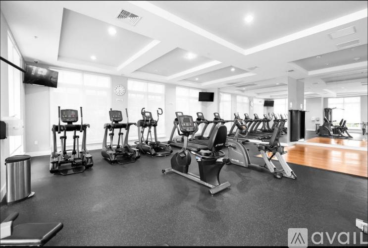 A gym with a variety of equipment including treadmills, stationary bikes, and elliptical machines.