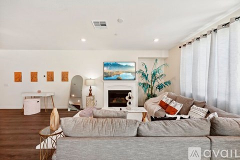 A living room with a grey couch, a fireplace, and a painting on the wall.