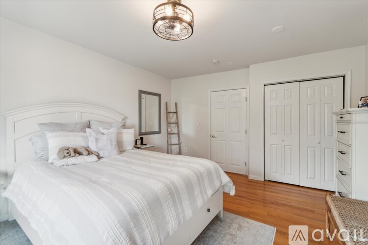 A bedroom with a large bed and a white color scheme.