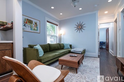 A living room with a green couch and a wooden chair.