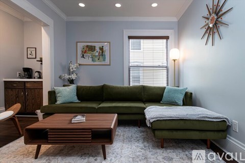 A living room with a green couch and a wooden coffee table.