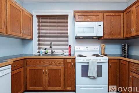 A kitchen with wooden cabinets and a white stove top oven.