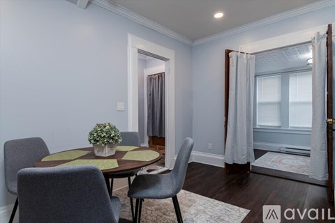 A dining room with a round table and grey chairs.