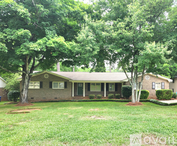 A house with a green lawn and trees in front.