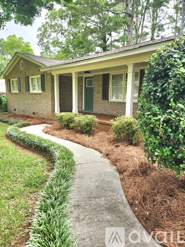 A house with a green lawn and a concrete pathway leading to the front door.