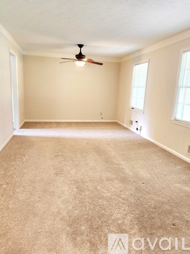 A spacious room with a ceiling fan and carpeted floor.