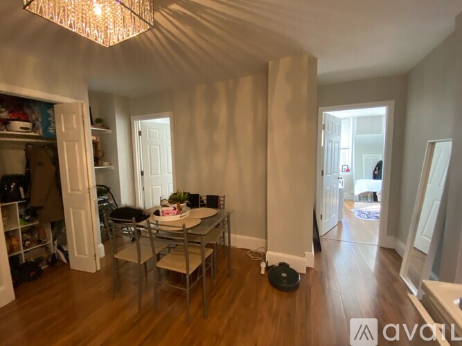 A dining room with a glass table and chairs, a chandelier, and a potted plant.