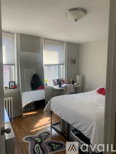 A bedroom with a bed, a mirror, and a dresser.