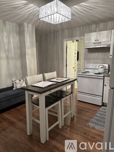 A kitchen with a table and chairs in the foreground and a stove in the background.