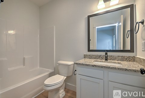 A bathroom with a toilet, sink, and mirror.