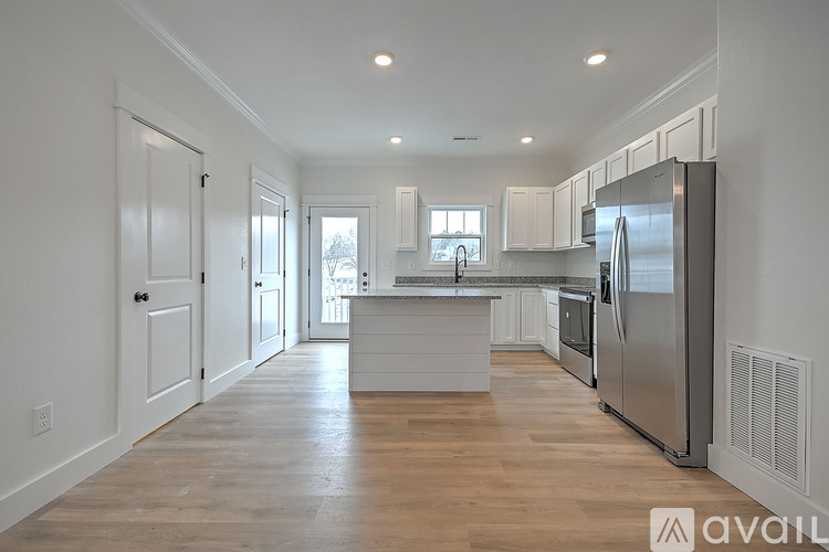 A kitchen with white cabinets and a wooden floor.