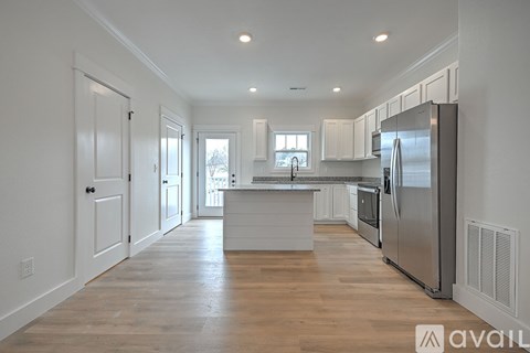 A kitchen with white cabinets and a wooden floor.
