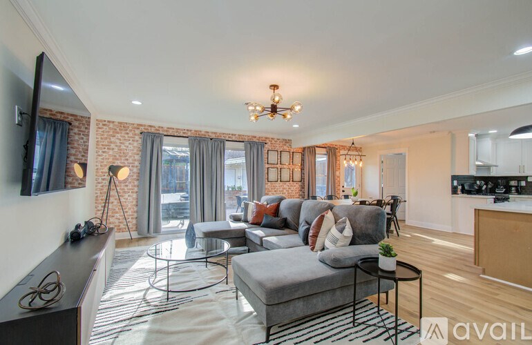 A living room with a grey couch and a chandelier.