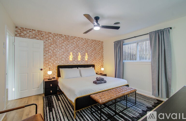 A bedroom with a brick wall and a bed with a wooden headboard.