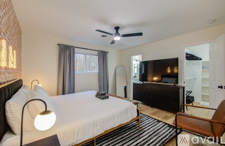 A bedroom with a bed, a chair, and a television.