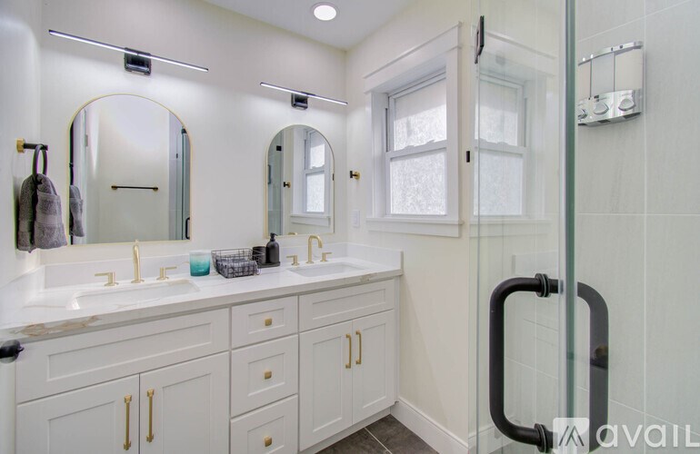 A bathroom with a white sink and gold handles.