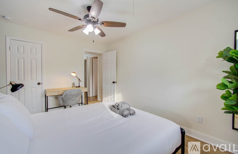 A bedroom with a bed, desk, and ceiling fan.