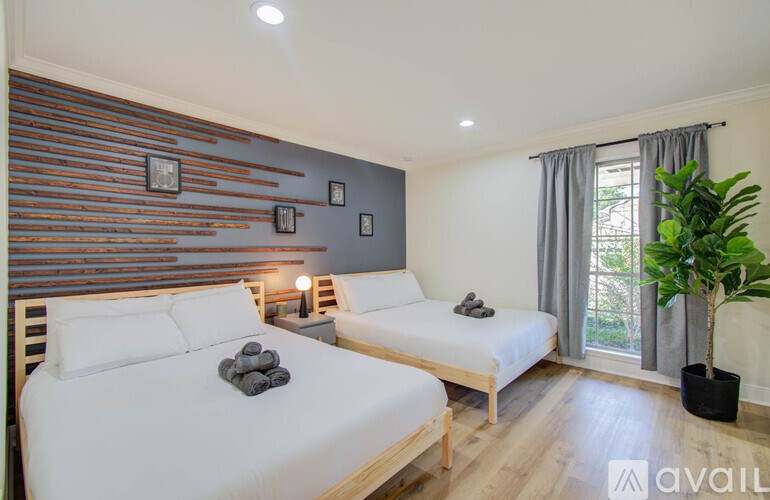 A bedroom with two beds and a wooden headboard.