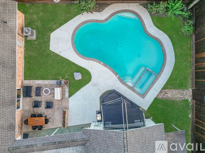 A swimming pool in a backyard with a hot tub and a grill.