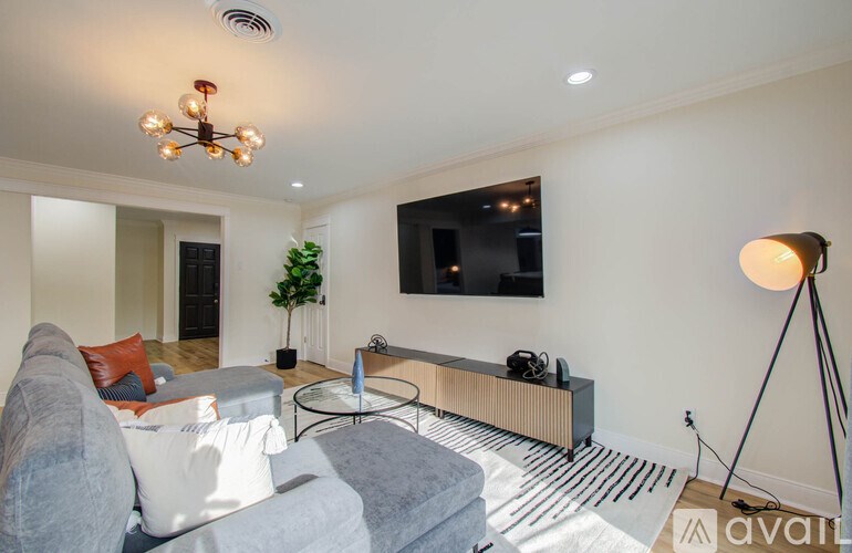A living room with a grey couch, a glass table, a television, and a floor lamp.