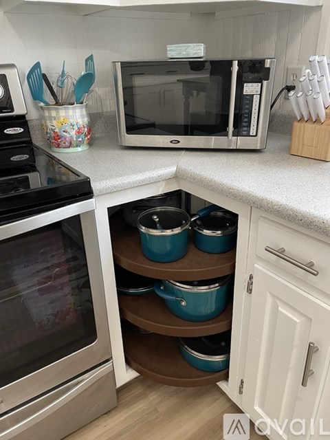 A kitchen with a stove, microwave, and a white countertop.