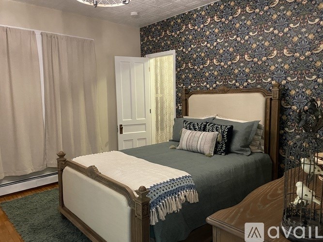 A bedroom with a large bed and a patterned wallpaper.