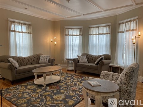 A living room with a grey sofa, a grey armchair, a white coffee table, and a rug with a floral pattern.