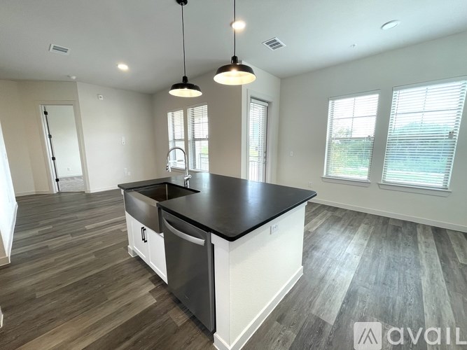 A kitchen with a black countertop and wooden flooring.