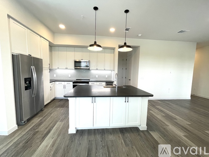 A modern kitchen with a refrigerator, microwave, and a center island.