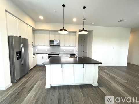 A modern kitchen with a refrigerator, microwave, and a center island.