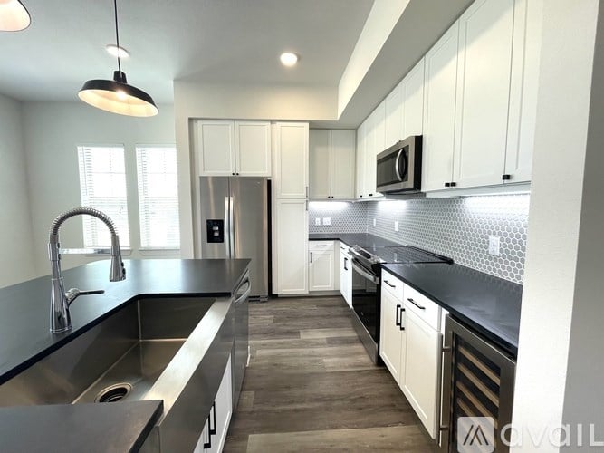 A modern kitchen with a black countertop and stainless steel appliances.