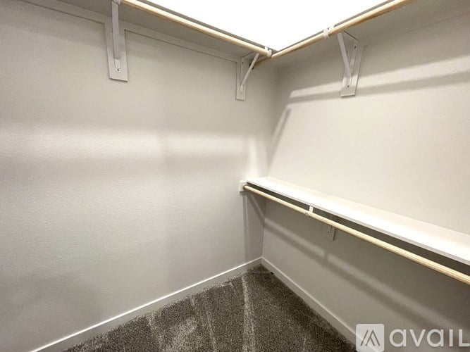 A white wall with a grey carpeted floor and a white shelf.