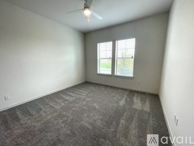 A room with a ceiling fan and a window overlooking a green area.
