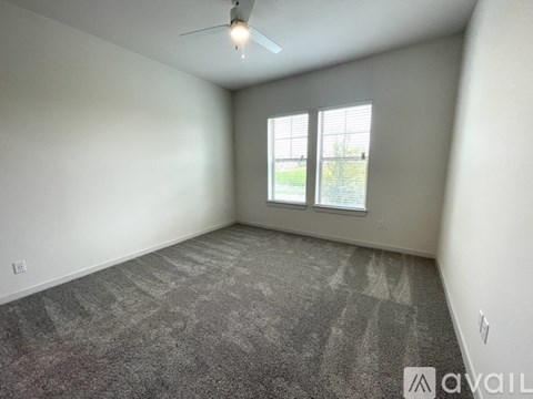 A room with a ceiling fan and a window overlooking a green area.