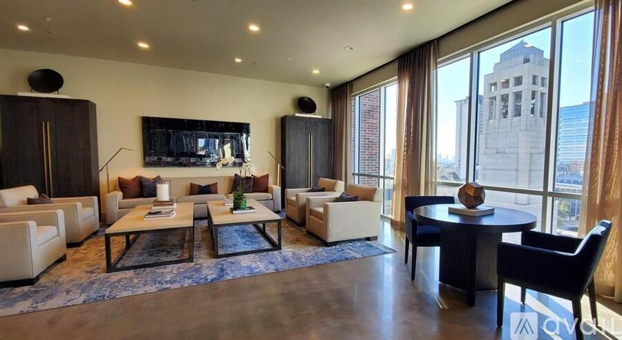 A living room with a large window and a view of a building outside.